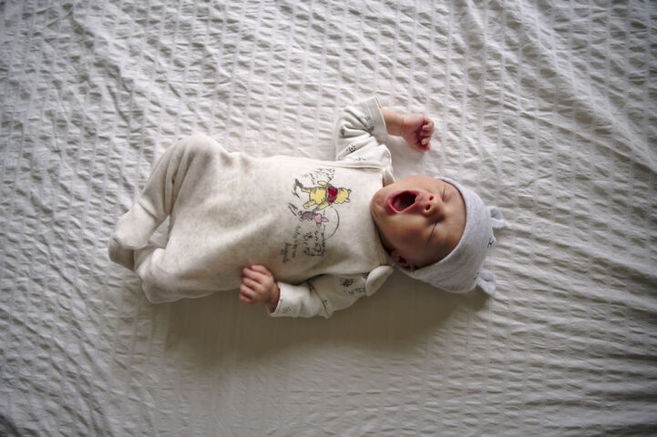 newbornfotograaf babyfotograaf Utrecht: lifestyle gapende baby liggend op bed